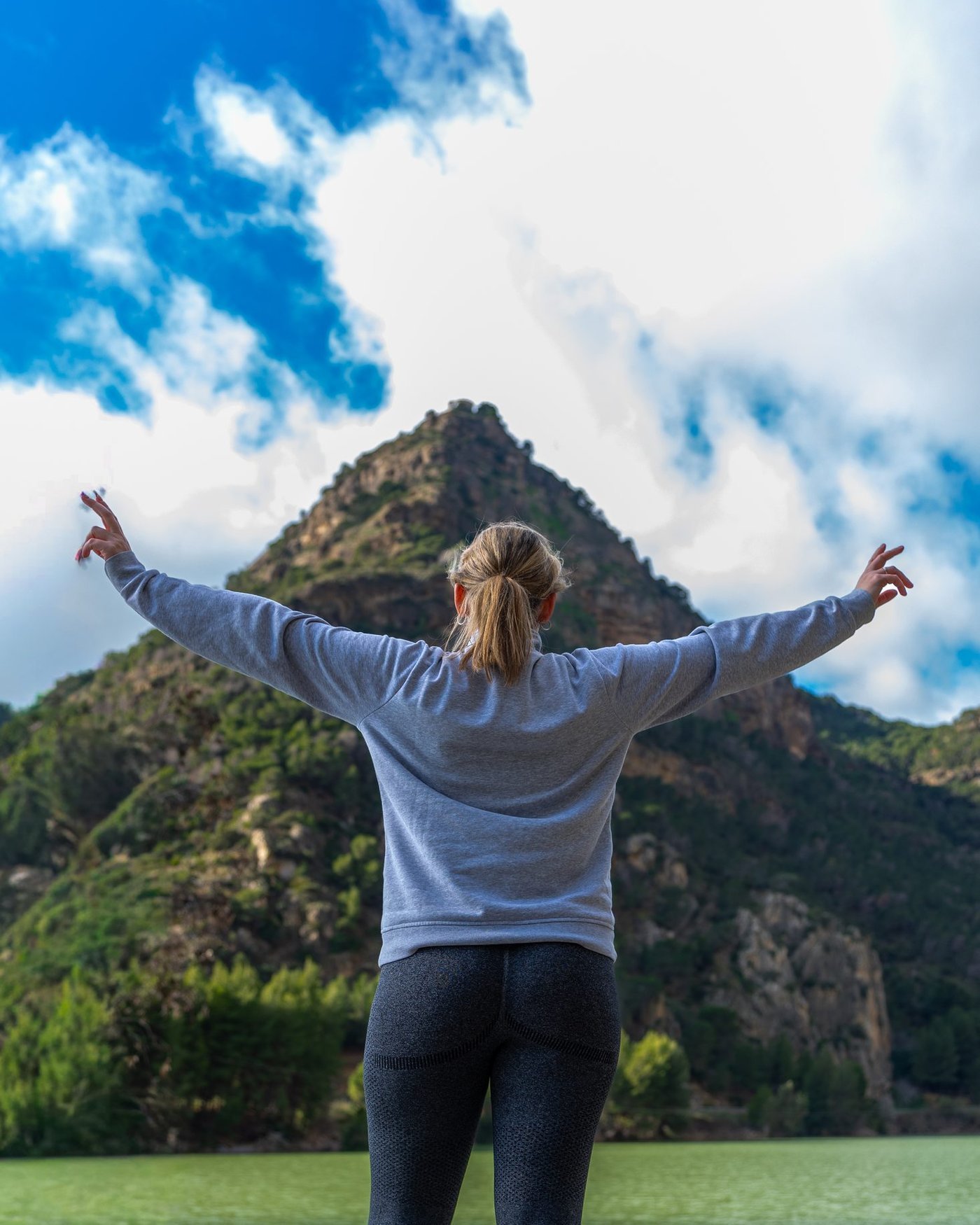 Mujer con los brazos abiertos frente a la montaña
